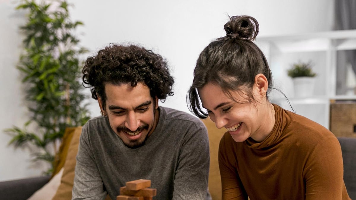 Husband wife playing wooden tower game home